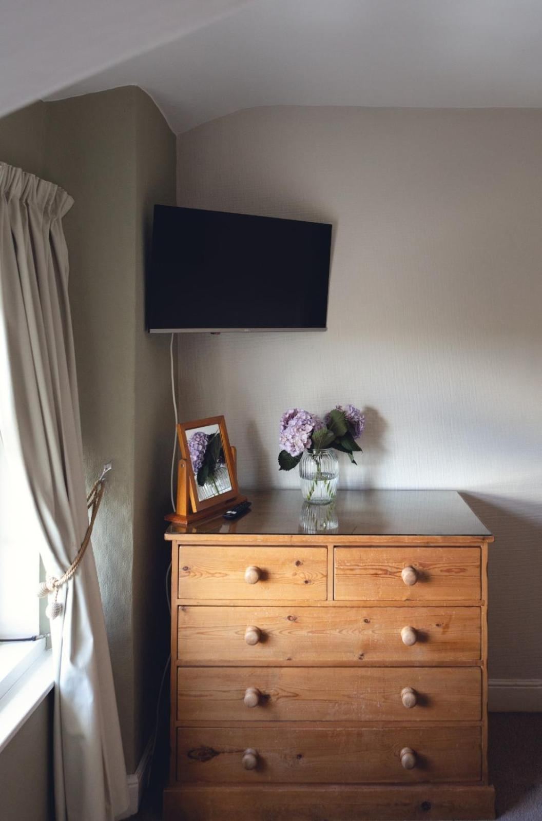 Pine dresser with wall-mounted television in a guest room