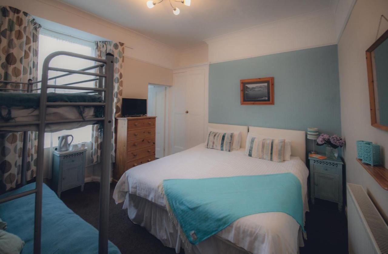 Family room with a double bed and metal bunk beds, teal bedding, leaf-pattern curtains